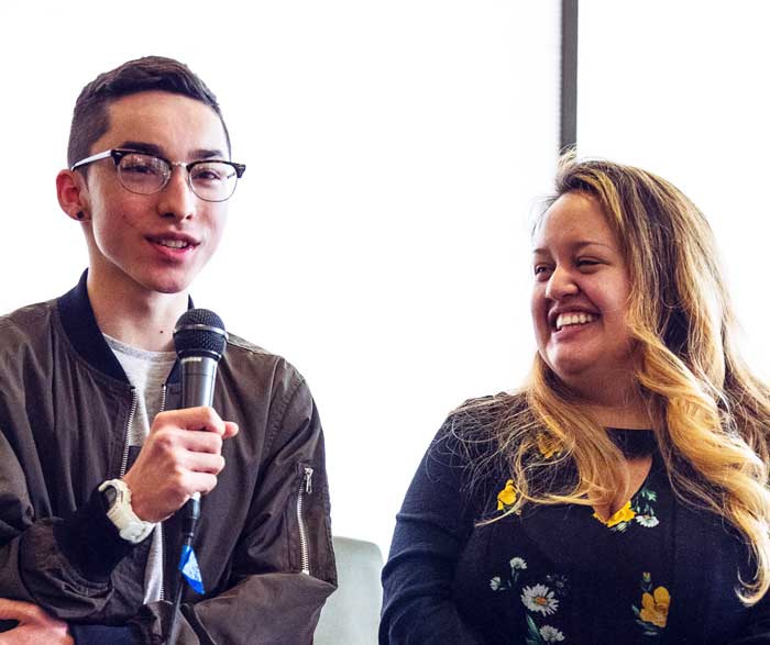 Collin Kazu Lewis holding a microphone while Chelsea Allison stands next to him smiling at him.