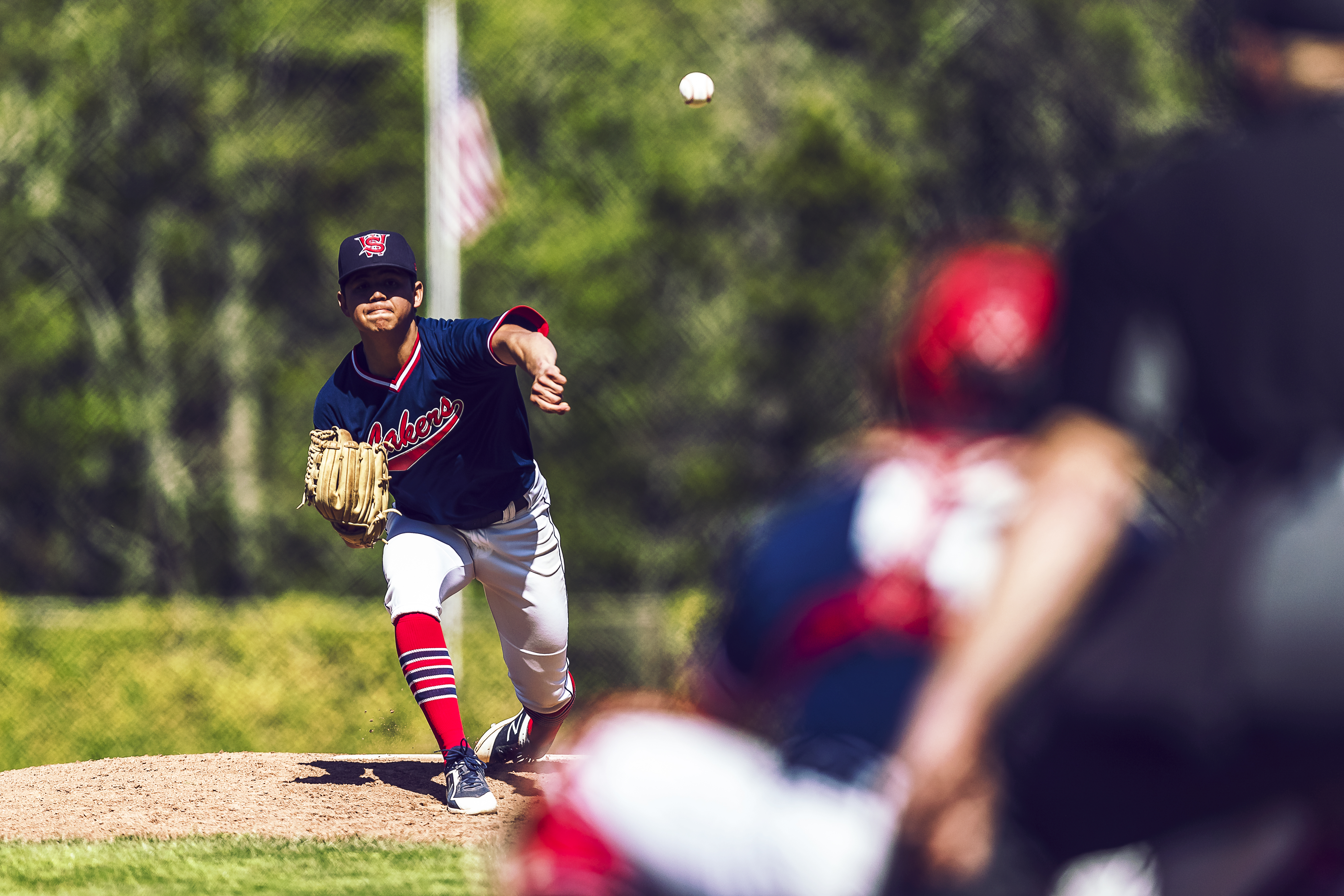 Lakers pitcher after throwing pitch with ball in midair headed toward umpire