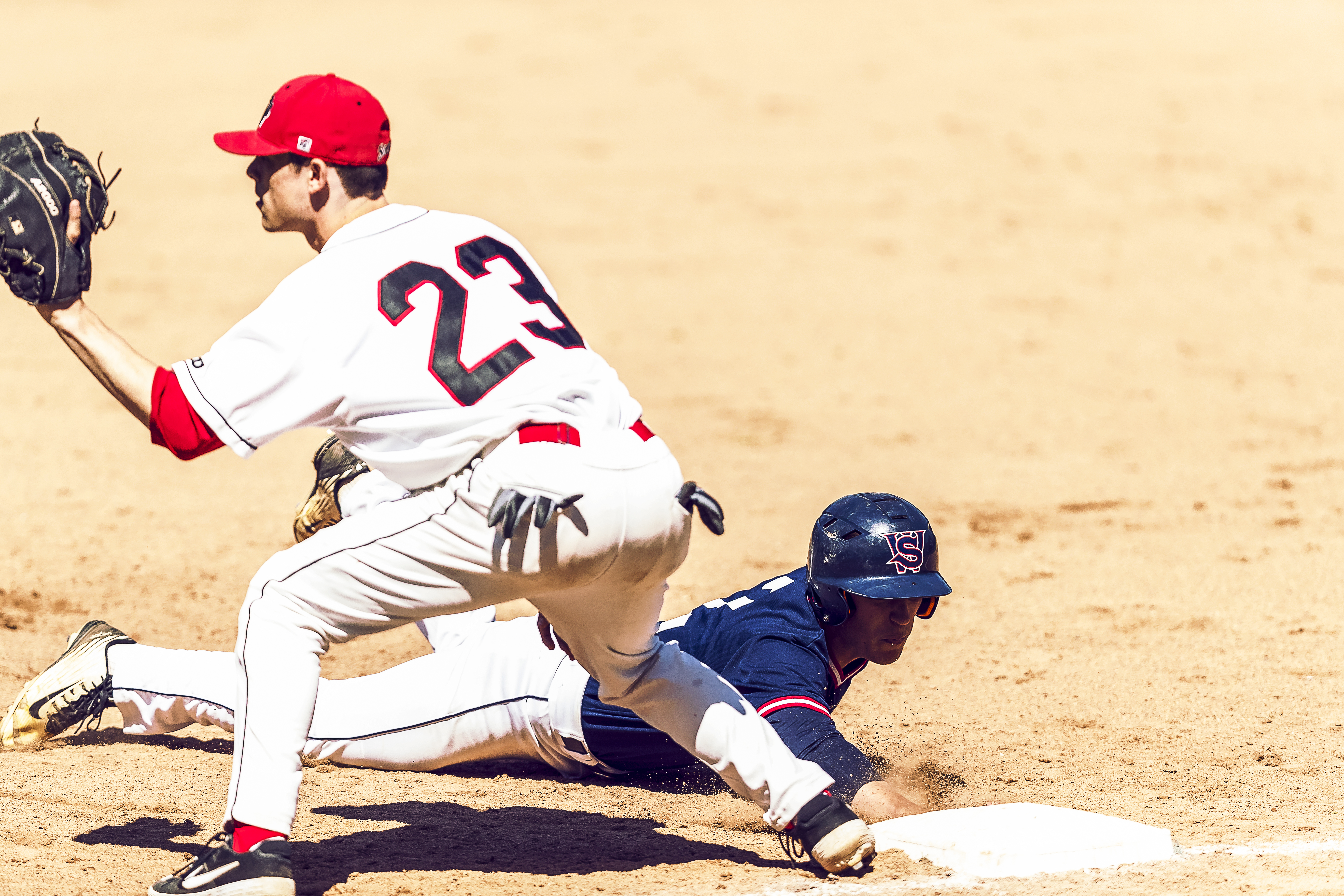 Lakers player sliding into a base as Saints number 23 prepares to catch ball