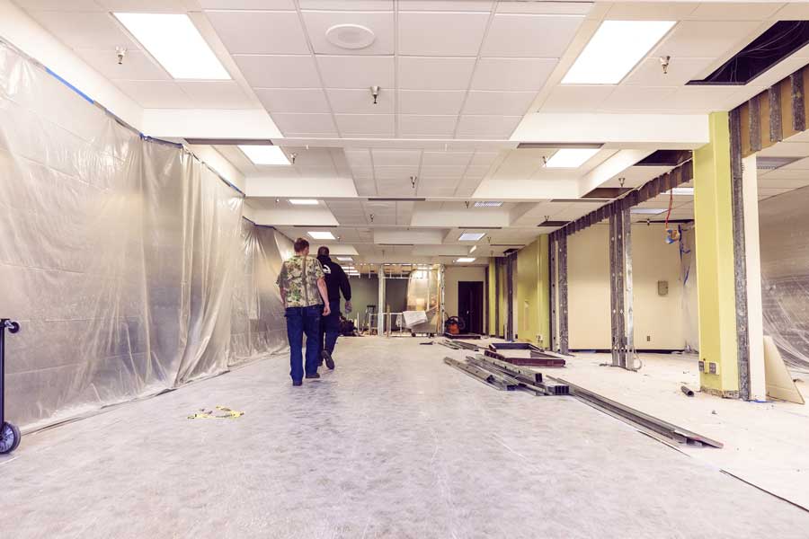 The new Student HUB is under construction with tarps and workers completing the blueprints.